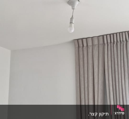 מנורה תלויה מהתקרה בחדר עם וילון